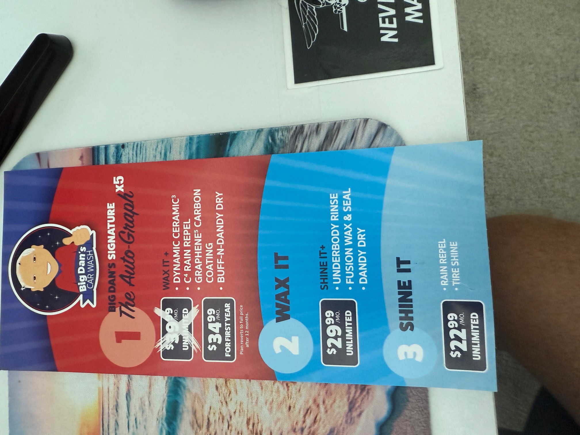Big Dan's Car Wash menu board showing the three unlimited membership tiers — The Auto-Graph x5 with its $39.99 monthly price crossed out to $34.99 for the first year, Wax It at $29.99 a month, and Shine It at $22.99 a month — with each tier's included features listed
