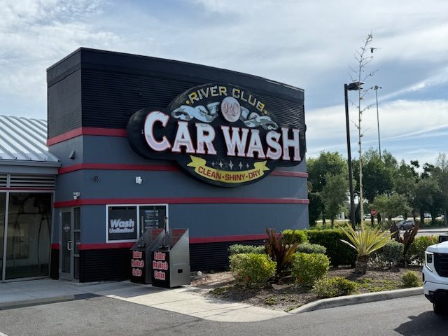 River Club Car Wash exterior signage at the 5740 Ranch Lake Boulevard location in Lakewood Ranch, Florida — glossy black building with gold lettering and red trim