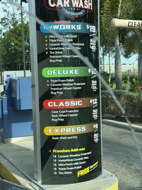 River Club Car Wash outdoor pricing board showing The Works at $19, Deluxe at $16, Classic at $12, and Express at $9, with unlimited monthly memberships alongside each tier